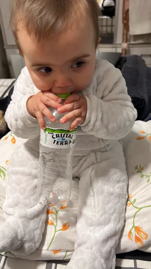 Joy segurando uma garrafinha de água com as duas mãos.